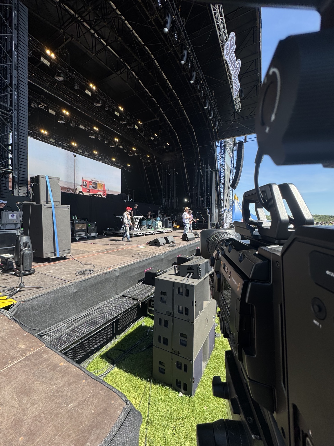 Broadcast camera overlooking a live festival stage